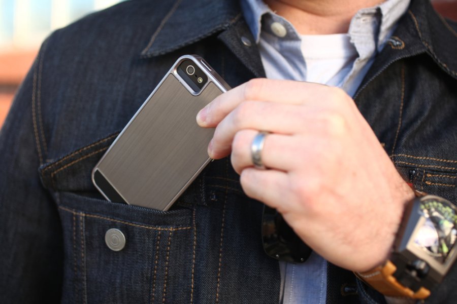Homem guarda celular no bolso da jaqueta jeans