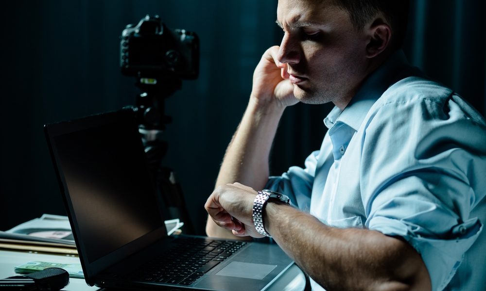 Detetive particular analisa material com notebook e câmera apoiados na mesa