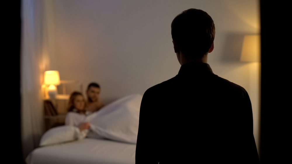 Homem observa casal em uma cama